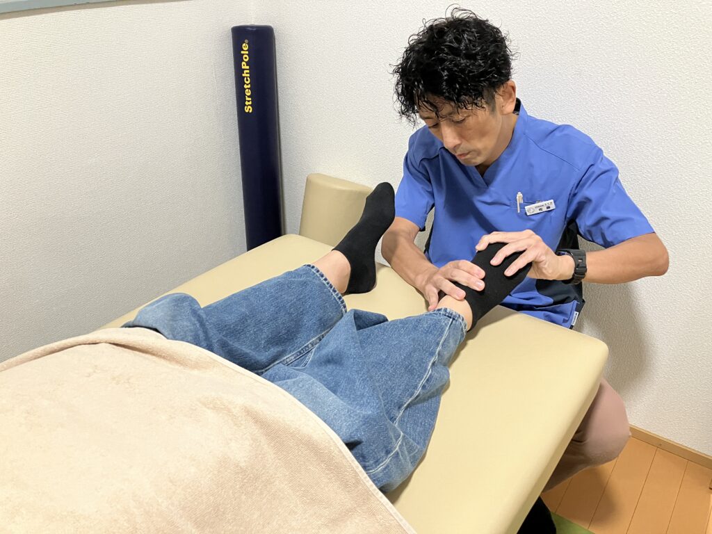 奄美市名瀬のBALANCECARE 接骨院 らくだ院長佐藤がやさしく足元の調整整体をしている写真