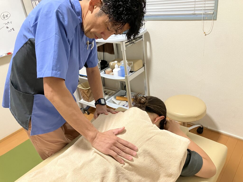 BALANCECARE 接骨院 らくだの院長佐藤が背中をやさしい整体でほぐしている写真