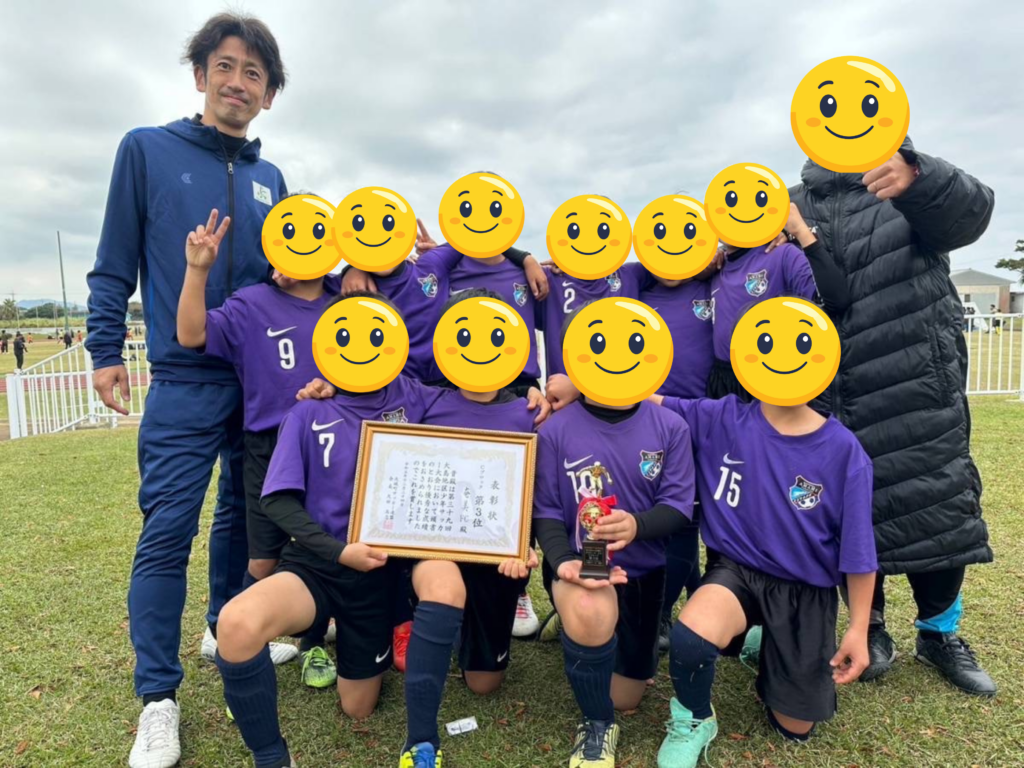 サッカー指導風景の写真(子どもたちに囲まれているところ) 徳之島遠征