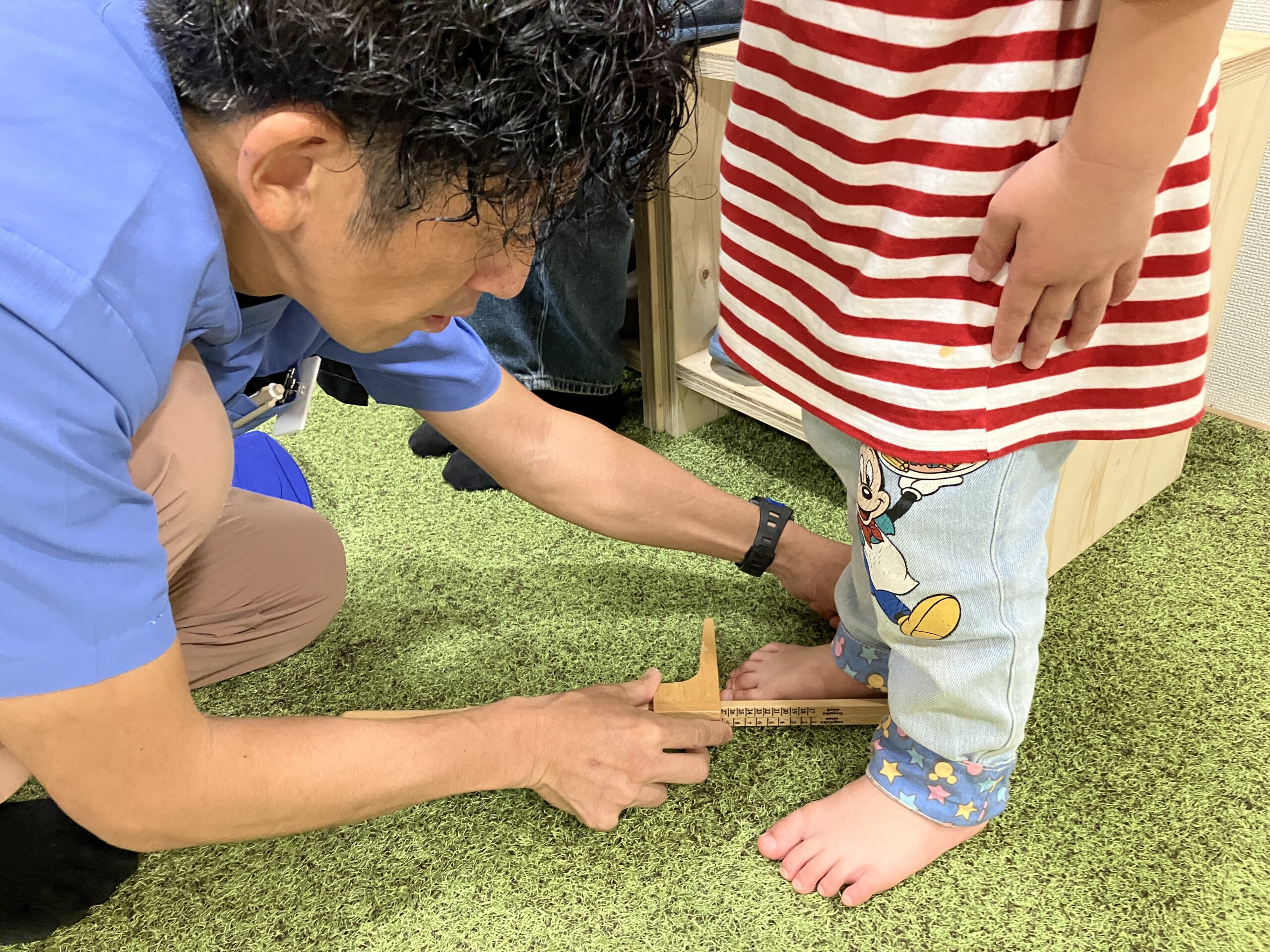 お子さんの足の長さをはかる佐藤洋一代表｜BALANCECARE 接骨院 らくだ