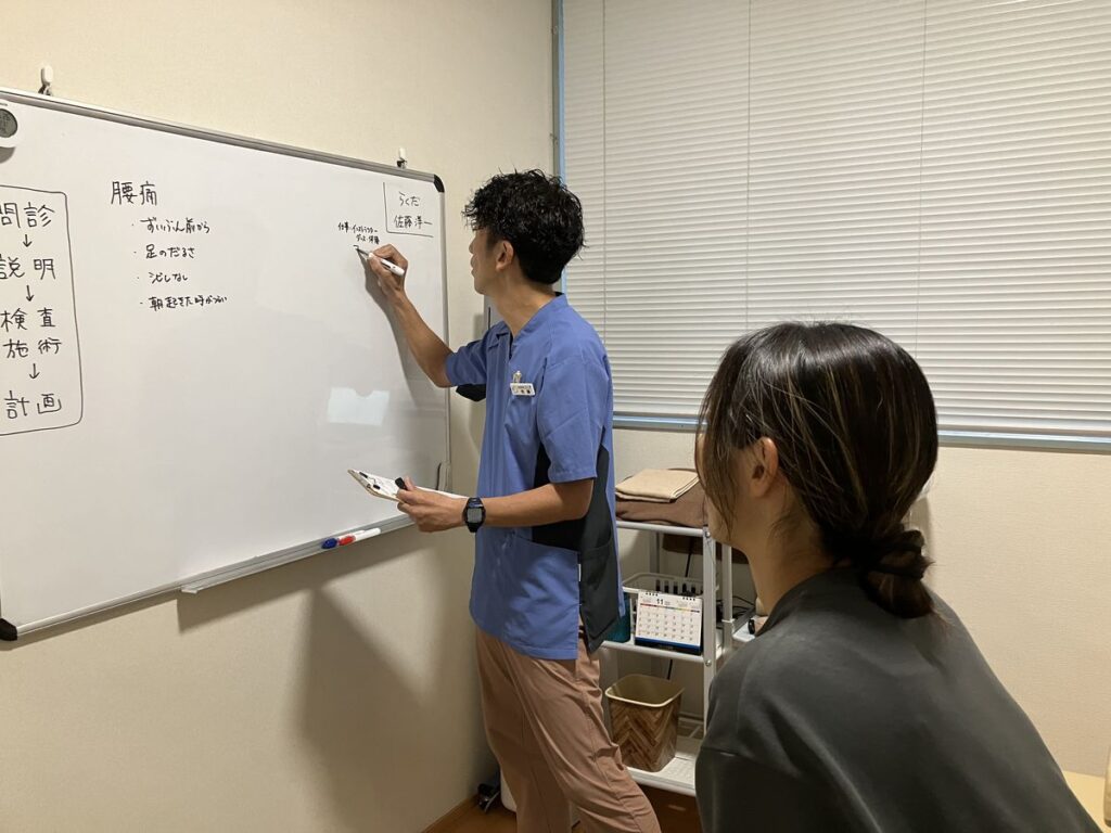 ホワイトボードで腰痛の原因を説明するBALANCECARE 接骨院 らくだの佐藤代表