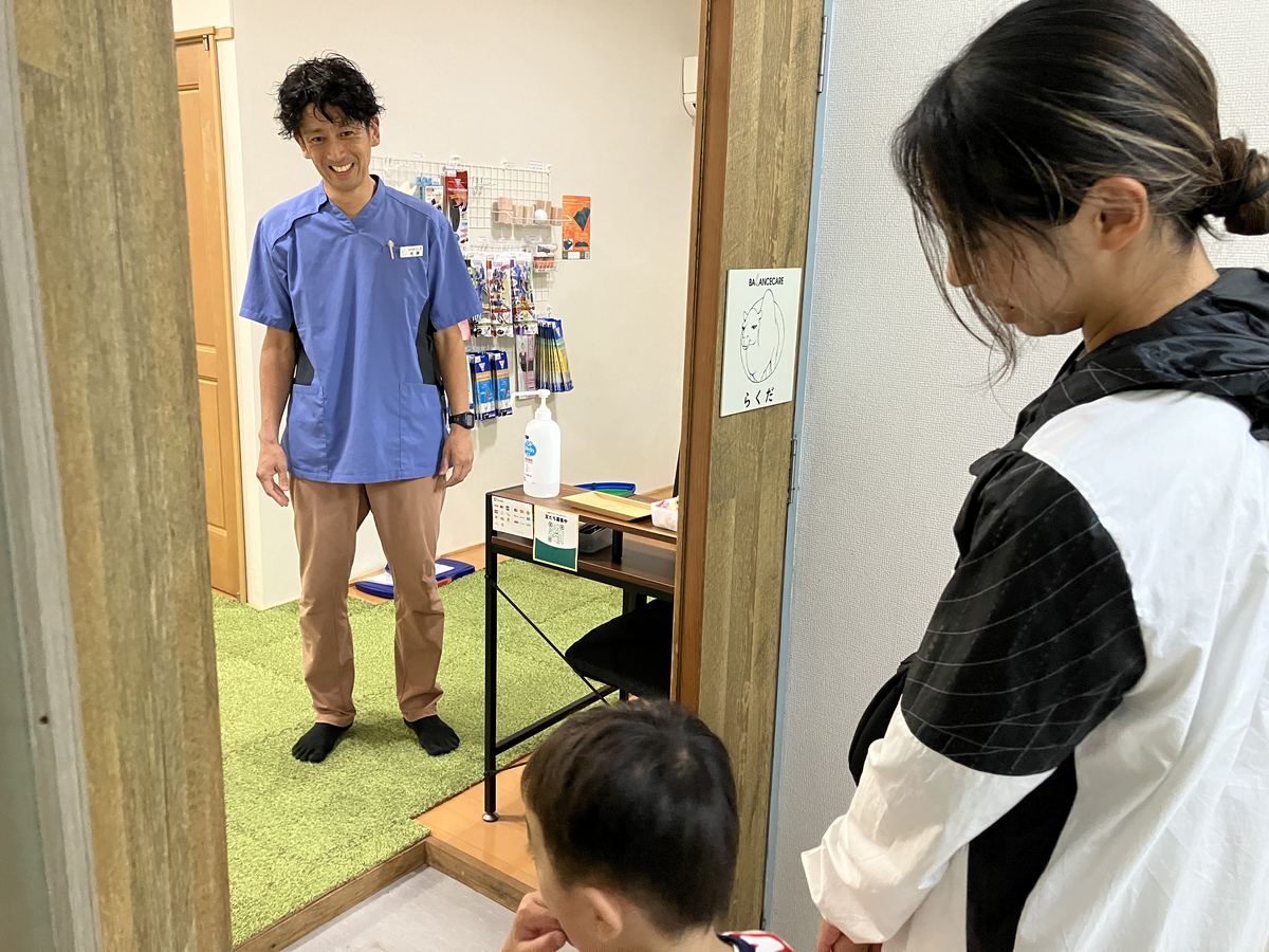らくだの看板の前で笑顔で出迎える佐藤洋一代表