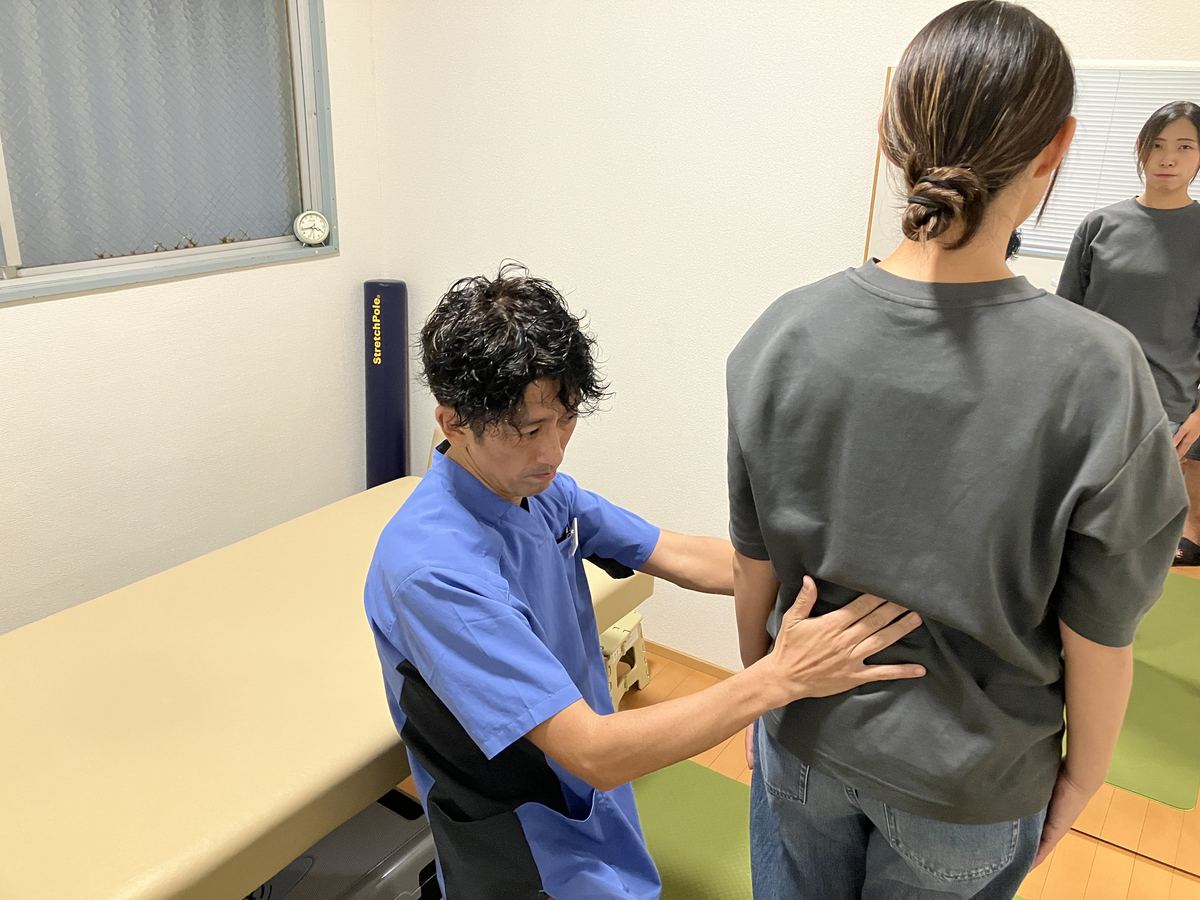 腰部を丁寧に触診して原因を確かめる佐藤洋一代表