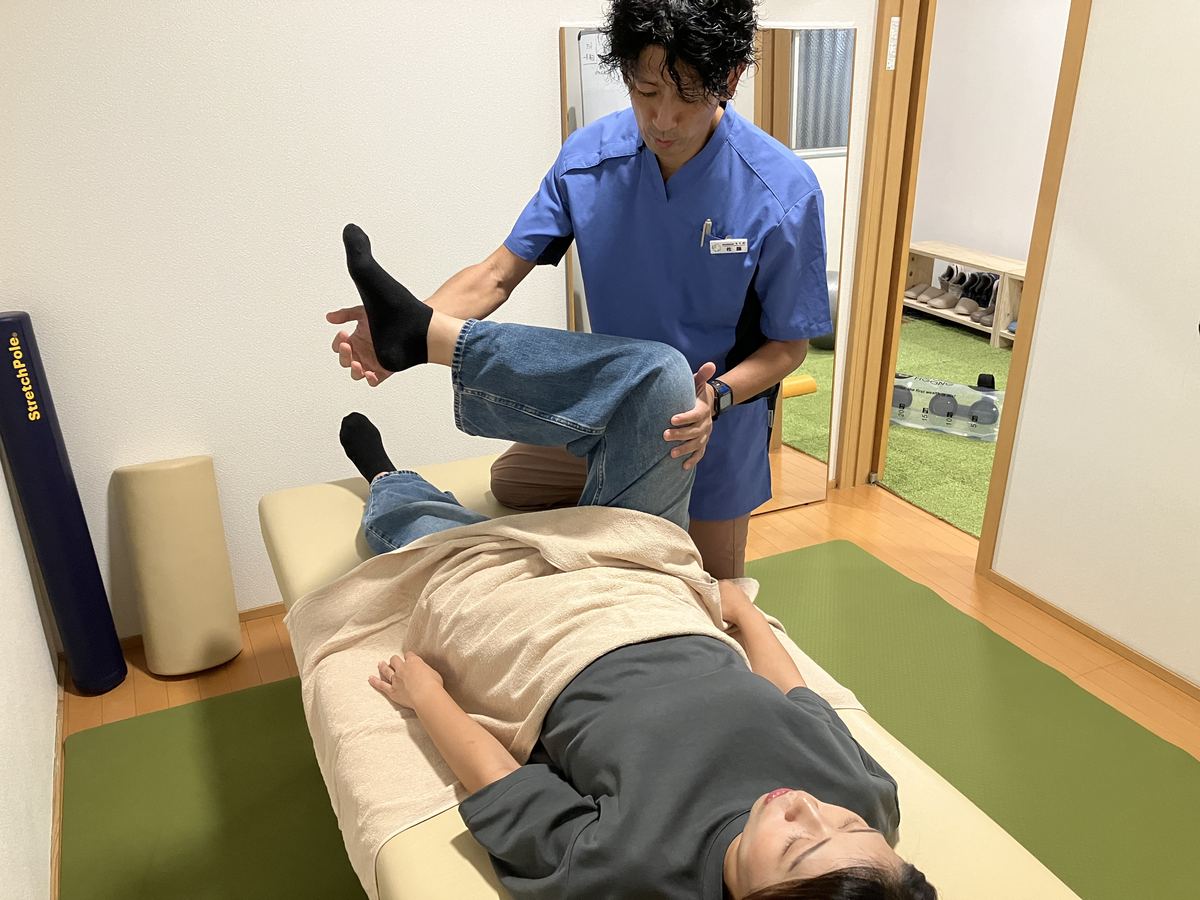 仰向けの患者さまにボキボキしないソフトな整体をおこなう佐藤洋一代表