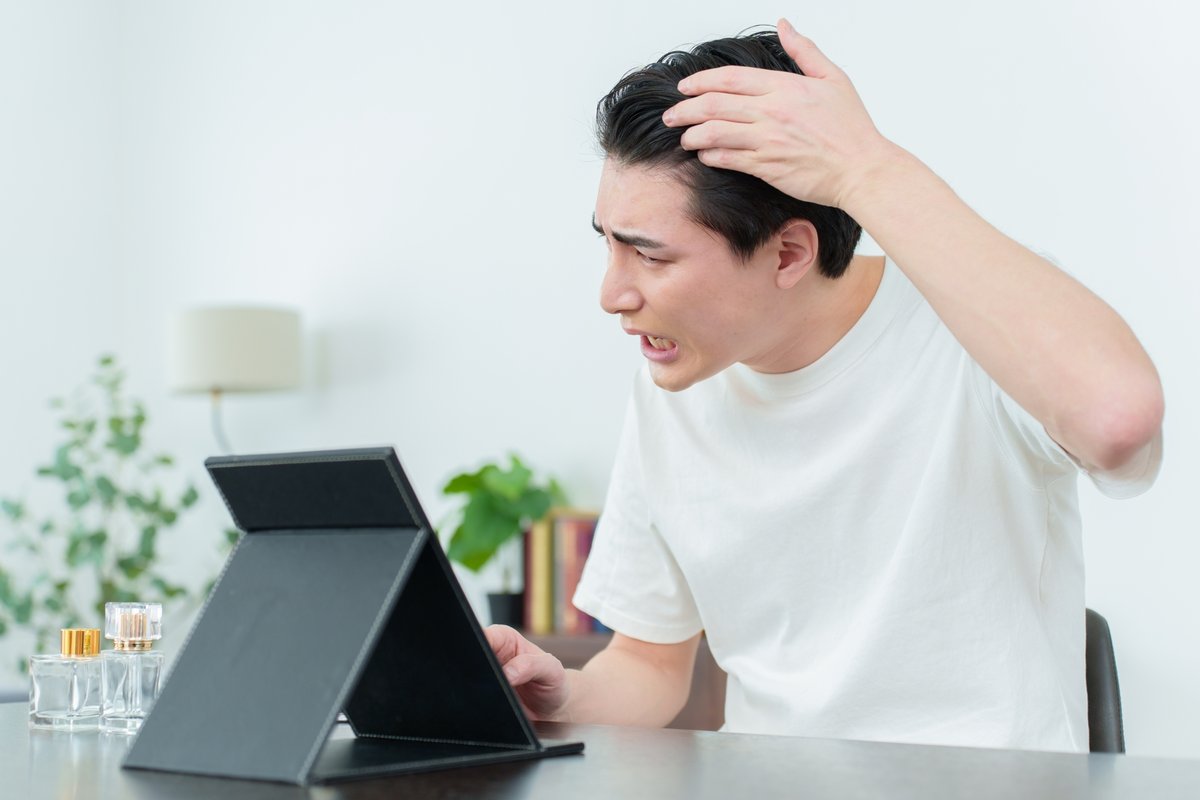 鏡で頭頂部の薄毛を気にする男性