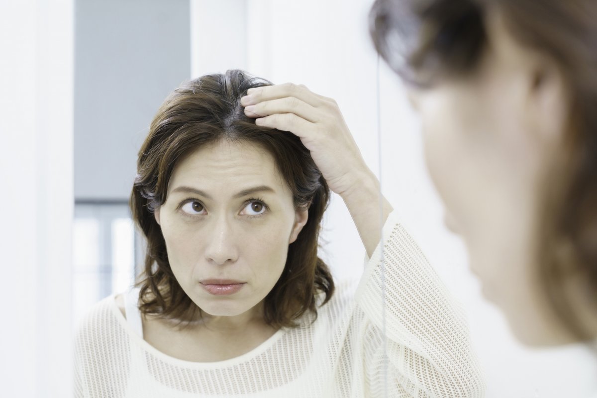 鏡で分け目の広がりを確認する女性